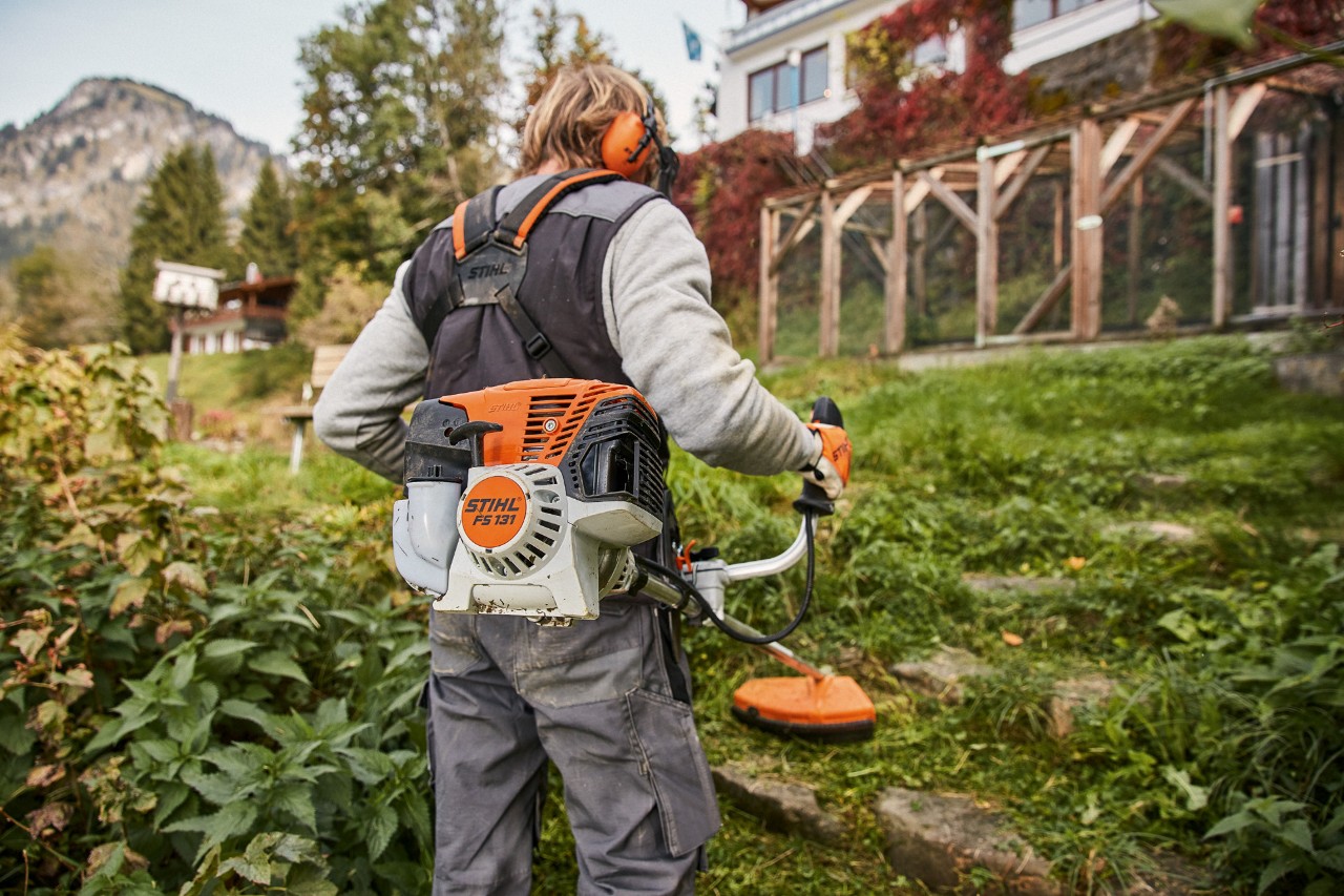 Pochyły teren przed domem jest koszony za pomocą benzynowej kosy mechanicznej STIHL FS 131 z silnikiem 4-Mix®